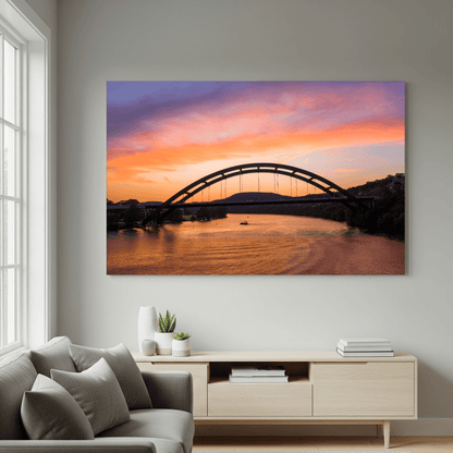 A modern living room with a gray sofa and wooden console, featuring the "Austin Glow" Pennybacker Bridge Sunset Print—The Wild in Focus's #1 Best Seller—perfect Texas decor for any Austin home.