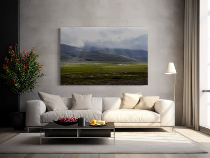 A modern living room with a light sofa, neutral pillows, black coffee table with fruit, floor lamp, green potted plant, and large Rivers of Light - Iceland Landscape Photography Print featuring misty mountains and grassy fields.