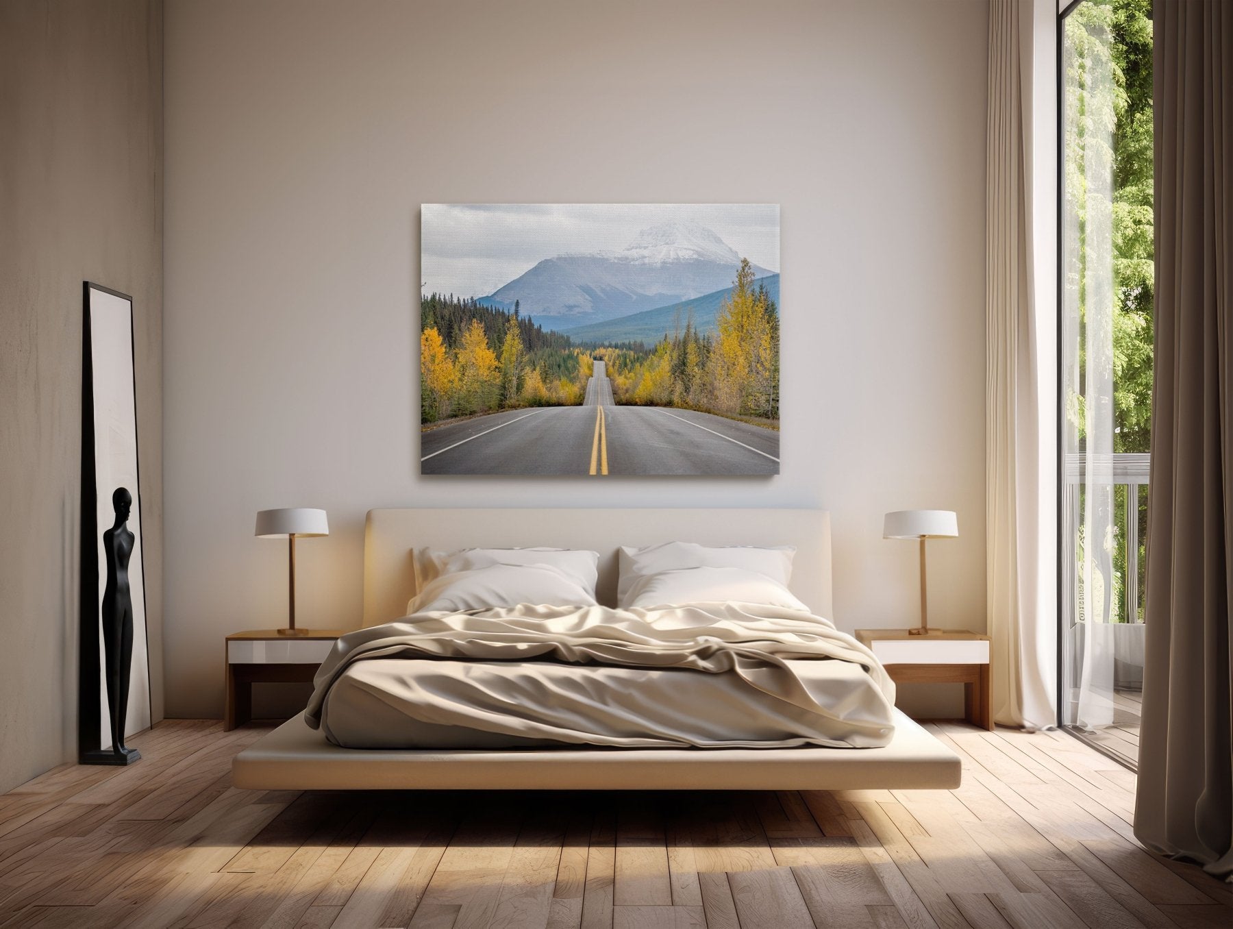 A modern bedroom featuring a low wooden bed with unmade beige bedding, two bedside tables with lamps, a floor mirror, and the "Road to Autumn | Icefields Parkway, Canadian Rockies Print" as striking wall art.